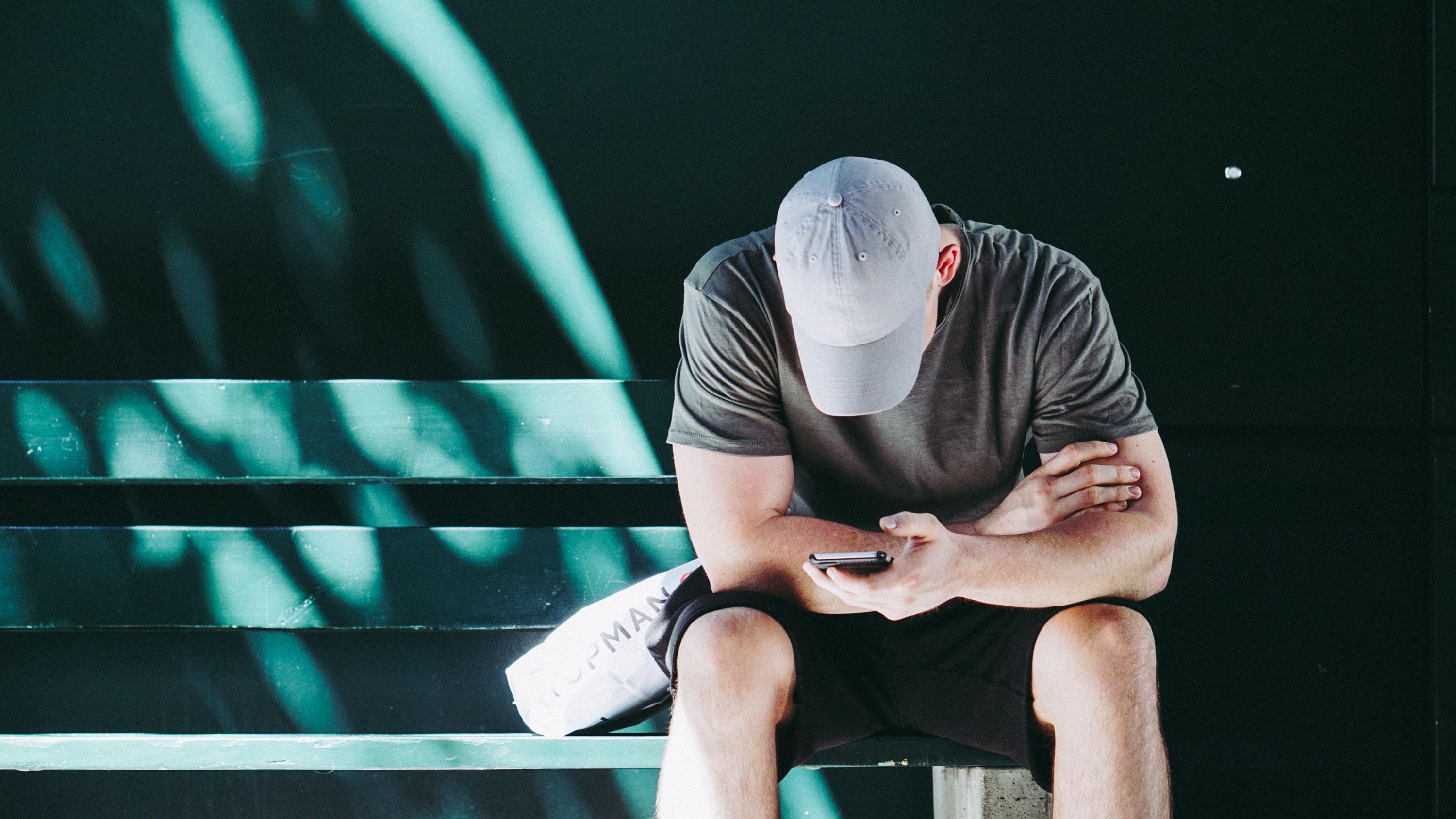 Man looking at phone with baseball cap